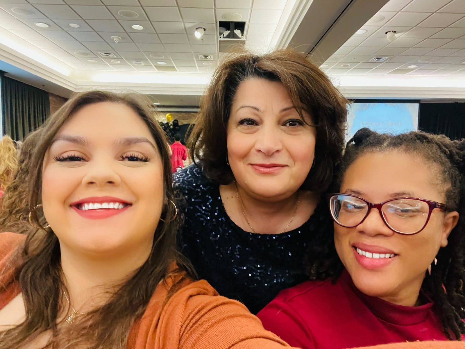 Three women smiling together at an event